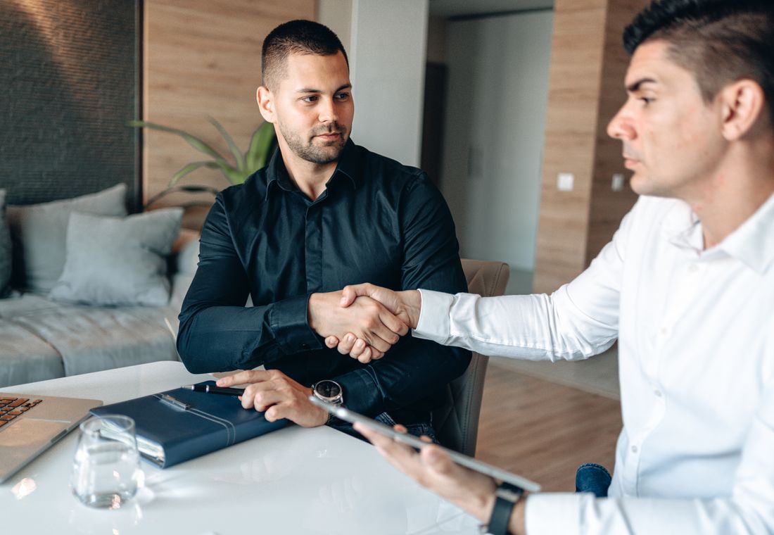 Two people shaking hands across a table after a meeting